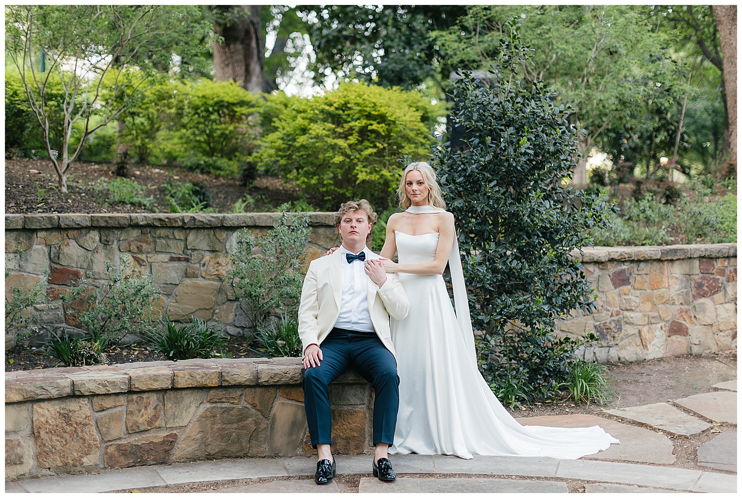 Bride and groom pose in a garden setting at Arlington Hall at Turtle Creek Park in Dallas, TX.